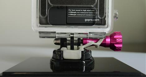 GoPro HERO3:n silikonisuojus kiinnitettynä mustaan pohjalevyyn ja vedenpitävän kotelon klipsiin.