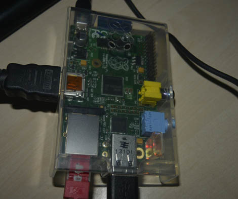 Raspberry Pi läpinäkyvässä muovikotelossa. Laitteeseen kiinnitetty virtajohto, HDMI-kaapeli, verkkokaapeli ja USB-piuha.